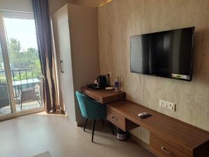 a room with a desk and a television on a wall at Aarush Hotel & Resort in Haldwāni +38 photos