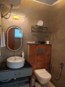 a bathroom with a sink and a toilet and a mirror at Aarush Hotel & Resort in Haldwāni