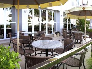 an outdoor patio with tables and chairs and umbrellas at Ibis Joao Pessoa Praia in João Pessoa
