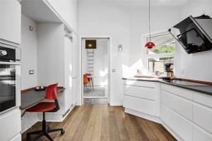 a kitchen with white cabinets and a red chair at SL245-Rude-Fuglevaenget-20 in Rude +23 photos