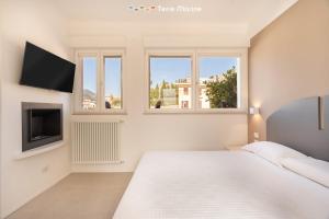 a white bedroom with a large bed and windows at Suite Level 8, Terre Marine in La Spezia
