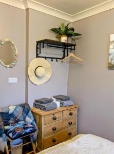 a bedroom with a dresser and a hat on a shelf at White Pebbles Appartment in Ilfracombe