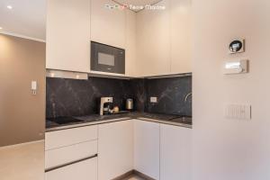 a kitchen with white cabinets and a tv on the wall at Suite Level 8, Terre Marine in La Spezia