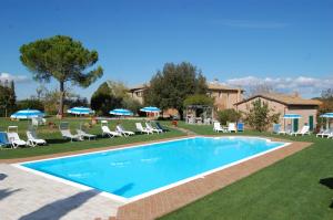 a swimming pool in a yard with chairs and umbrellas at Agriturismo San Giorgio in Monteroni dʼArbia