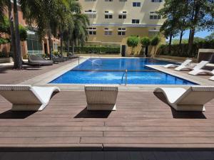 a swimming pool with white chairs and a building at Cozy Studio Long Stays Welcome in Biñan