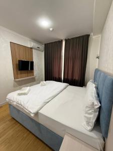 a bedroom with a large bed and a television at Avenue Hotel Tashkent in Tashkent