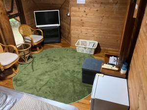 a living room with a tv and a green rug at PrivateVillaHutamiLog in Nago