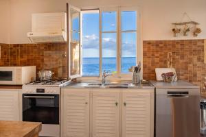 a kitchen with a sink and a view of the ocean at Villa MARION bord de mer in Pino