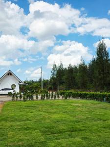 a field of grass with a house in the background at Kanchana home stay กาญจนา โฮมสเตย์ สุราษฏร์ in Ban Bo Thong