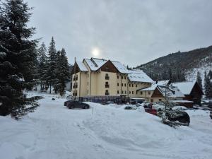 a large building in the snow with cars parked at Apartman Lúčky-Rea in Belá