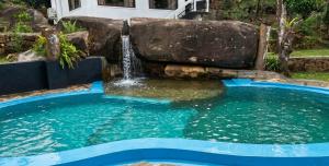 a swimming pool with a waterfall in a backyard at Visbury Villa in Gangaboda
