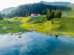 an aerial view of a house on a hill next to a lake at Berghotel Kleiner Biber in Warth am Arlberg