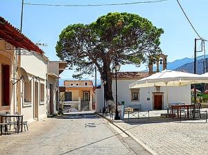a street with a tree and tables and an umbrella at Villa Andrianna in Frés