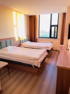 two beds in a room with two large windows at Onon-Ulz restaurant and hotel in Uldz