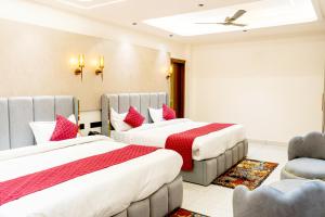a hotel room with two beds and a chair at Hotel Panipat Prime in Pānīpat