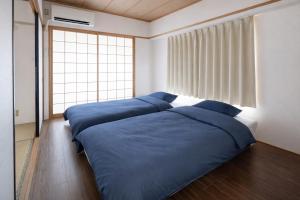 a bedroom with two beds with blue sheets and a window at マンションメゾンV206 maisonV206 in Gifu