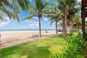 a beach with palm trees and chairs on the sand at Sea Casa Ho Tram - Villa nghỉ dưỡng sát biển Hồ Tràm in Xuyên Mộc