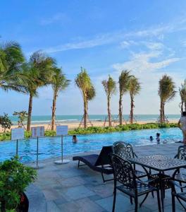 a swimming pool with palm trees and a beach at Sea Casa Ho Tram - Villa nghỉ dưỡng sát biển Hồ Tràm in Xuyên Mộc