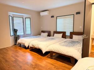 three beds in a room with wooden floors and windows at Izu Plateau House 420 square meters, BBQ , 8 bedrooms, 1 living room 1kitchen 6 toilets 4 bathroom 1 onsen in Yawatano