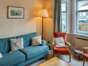 a living room with a blue couch and a chair at The Castaway in Mundesley