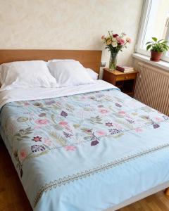 a bed with a blue blanket with a vase of flowers at Hostellerie de la juhel in Villaines-la-Juhel
