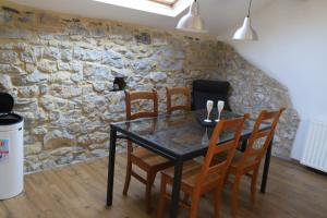 a dining room table with chairs and a stone wall at Pause-toit, Le gîte de Mozet. in Gesves +3 photos