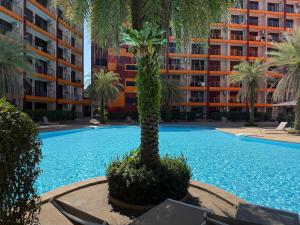 a swimming pool with a palm tree in front of a building at Mai Khao 777 Beach Condo in Ban Mai Salae