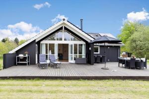 a black house with a deck and an umbrella at 20134-Samso-Heden-19 in Nordby