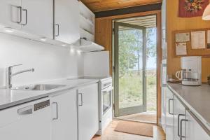 a kitchen with white cabinets and a sink at 20119-Samso-Maarup-Skov-26 in Nordby +17 photos