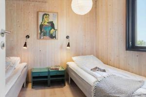 a bedroom with two beds and a table and a painting at 20220-Samso-Rosenvej-25 in Tanderup
