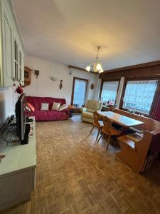 a living room with a red couch and a table at Calvi's Center Home in Auronzo di Cadore