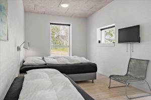a bedroom with two beds and a tv and a chair at 20503-Samso-Strandkrogen-37 in Sælvig