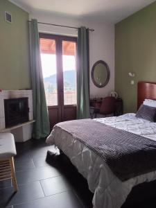 a bedroom with a bed and a large window at Petra & Elato Art Hotel in Valtessiniko