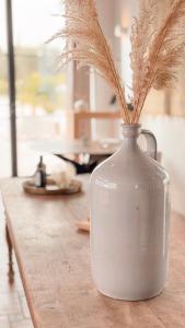 a white vase with grasses in it on a table at Finca las Calmas Adults Only Boutique Retreat & Dining Experience in Moraleda de Zafayona
