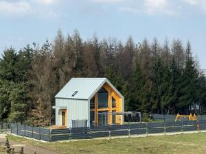 a small house in a field with a fence at Parkcity SPA Domek z jacuzzi w górach in Biała Niżna