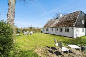 a white house with chairs and a table in a yard at 20322-Samso-Bakkevej-7 in Brundbymark