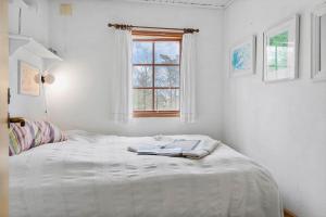 a white bedroom with a bed with a window at 20132-Samso-Skovvejen-7 in Nordby