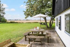 a picnic table with an umbrella next to a field at 20509-Samso-Egevej-13 in Onsbjerg