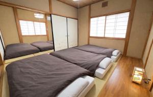 a bedroom with two beds and two windows at Guesthouse すえ in Mashizume