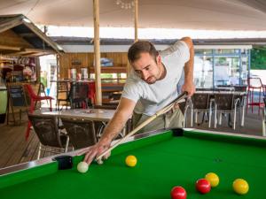 a man playing pool with a cue on a pool table at Flower Camping Le Pont du Tarn in Florac