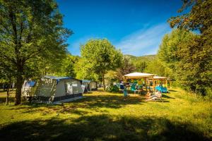 a group of people sitting in the grass next to tents at Flower Camping Le Pont du Tarn in Florac