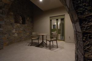 a table and chairs in a room with a stone wall at Anopoli Rooms in Sinoikismós Kámbos +27 photos