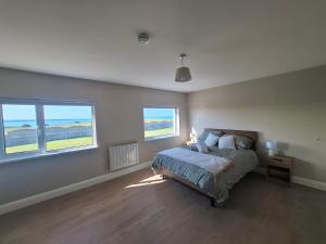a bedroom with a bed and two windows at Cliff Top Accommodation in Spanish Point