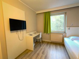 a room with a bed and a desk and a television at Bendorf Hotel by Belvilla in Bendorf +40 photos