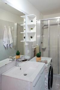a white bathroom with a sink and a shower at Ca di baragett in Mandello del Lario +6 photos