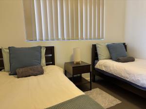 a bedroom with two beds and a window with blinds at Courtyard apartment in Perth