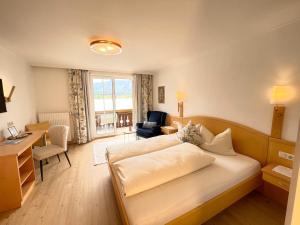 a bedroom with a bed and a desk and a chair at Hotel Garni Buchinger in St. Wolfgang