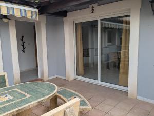 a patio with a table and a glass door at Sol-Y-Days Avenue Camargue, grande maison proche centre et mer in Le Grau-du-Roi