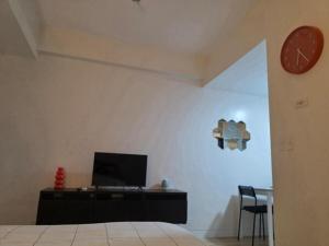a room with a desk with a tv and a clock at Cozy Studio Long Stays Welcome in Biñan