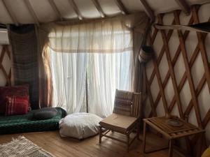 a room with a bed and a chair and a window at Meek Yurt in Yodefat